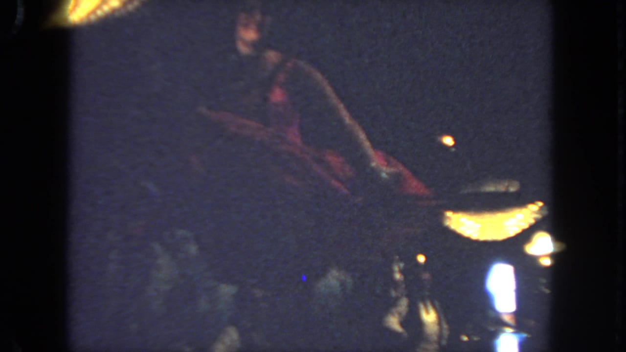 Cancan dancer in a red costume performs on a dark stage under warm lights.