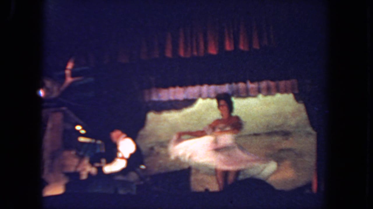 Woman in a white dress spins on a dim stage beside a keyboard player.