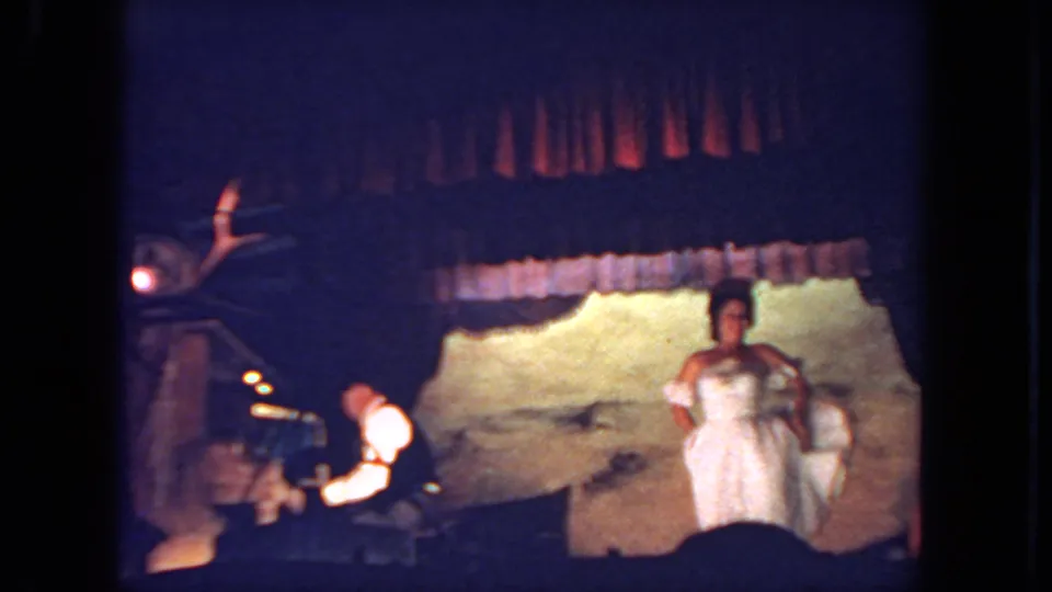 A 1962 San Diego stage frame shows the dancer facing forward in a white dress, with a musician at a keyboard on the left.