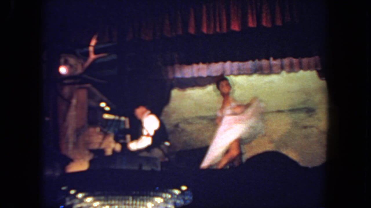 Dancer in a white dress lifts her costume while a pianist plays on the left side of the stage.