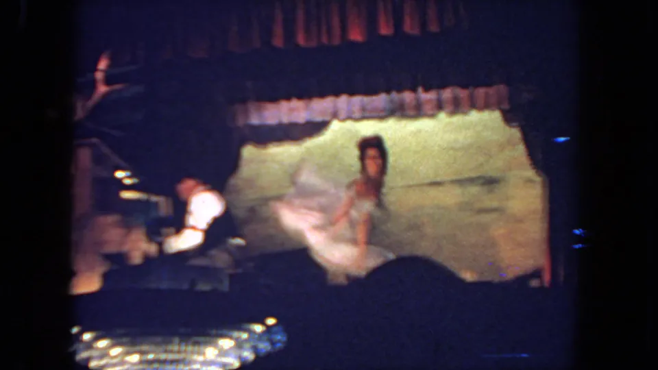 In 1962 San Diego footage, a woman in a light dress moves onstage while a seated keyboardist plays at the left.