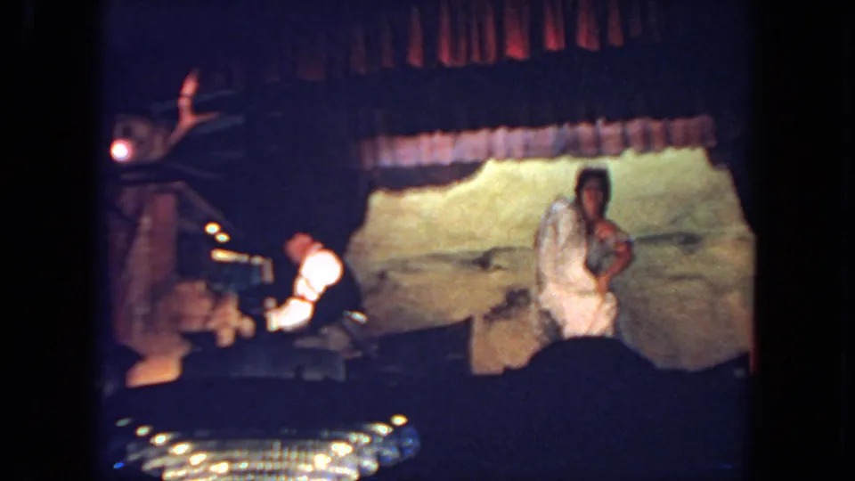 The stage view shows the woman near the backdrop and the keyboardist at left in grainy 1962 home-movie footage.