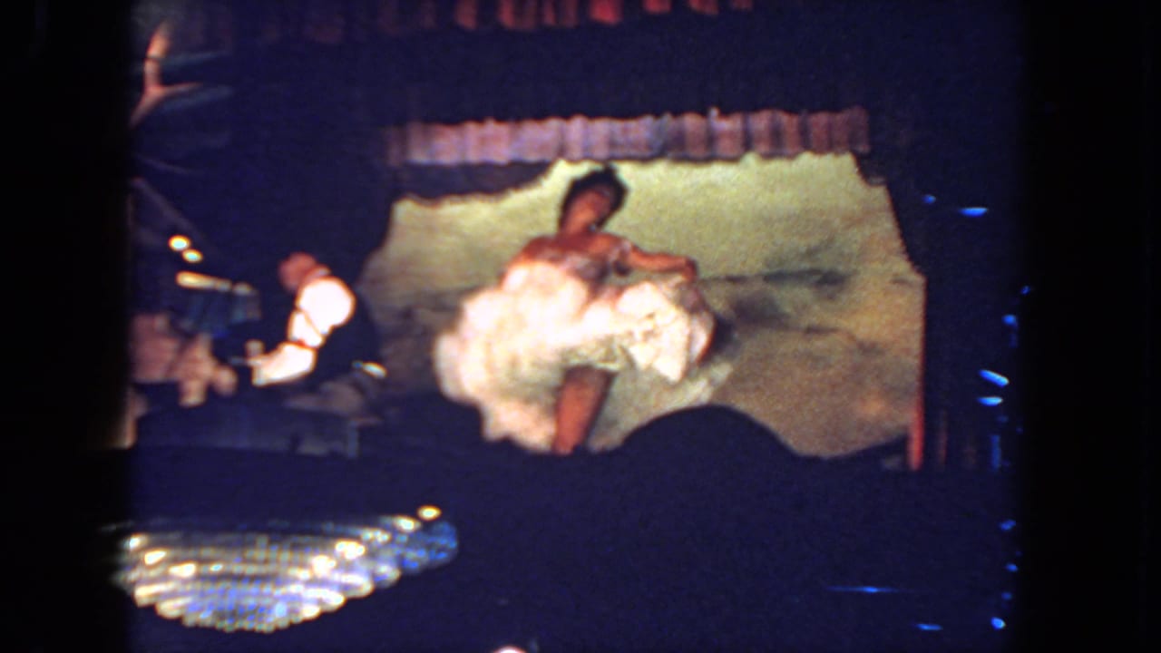 Bride in a white gown dances on a dim stage beside a pianist at a piano.