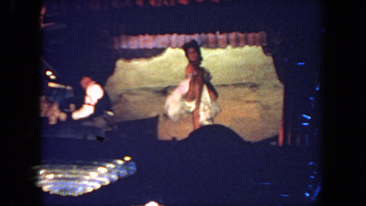Bride faces the audience on stage while the pianist continues playing at the piano.