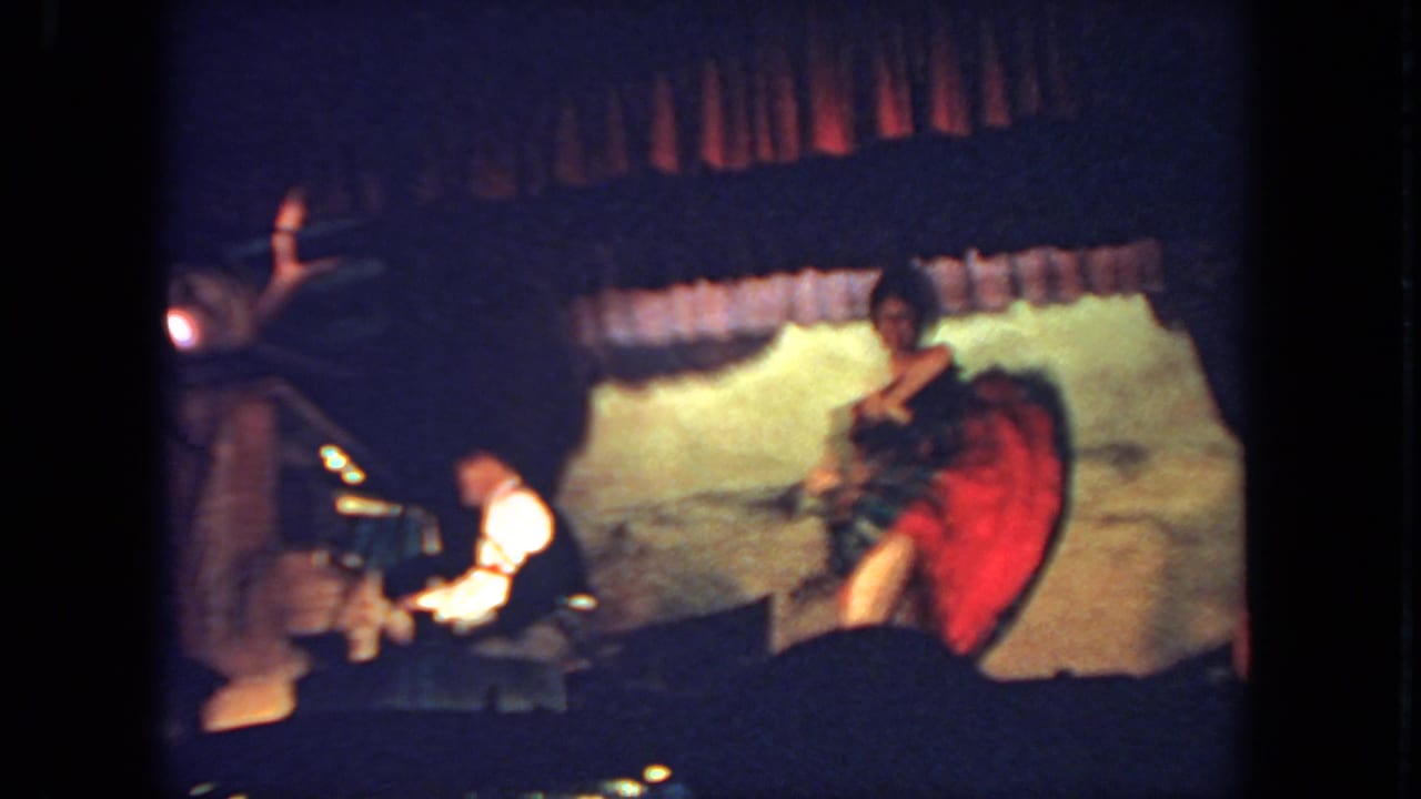 A stage dancer twirls her dress, revealing a red underskirt, as the seated pianist remains at the piano.