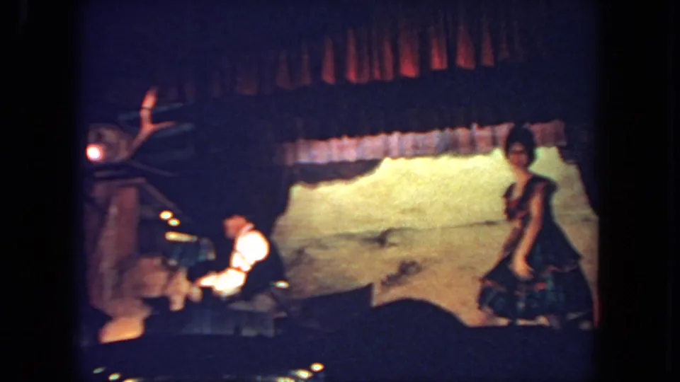 The dancer pauses or steps toward the right side of the stage as the pianist continues playing at left.
