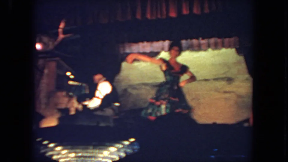 Audience-shot 1962 San Diego 8mm frame with a dancer in motion, pianist at left, and theatrical backdrop behind them.