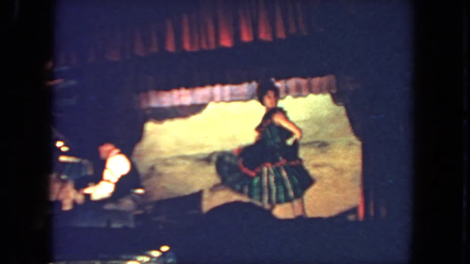 San Diego 1962 8mm frame showing the dancer turned toward the backdrop, with a pianist and piano visible at left.