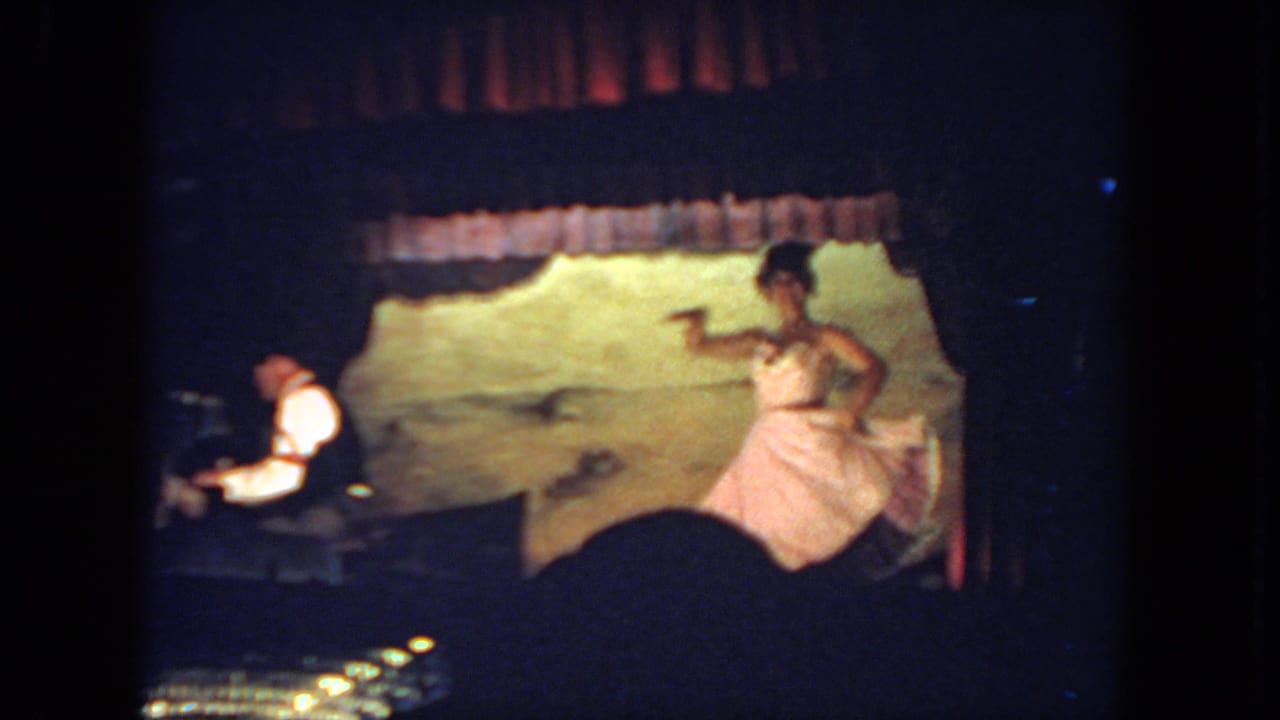 Dancer in a pink dress gestures across the stage as the pianist remains seated at the piano.