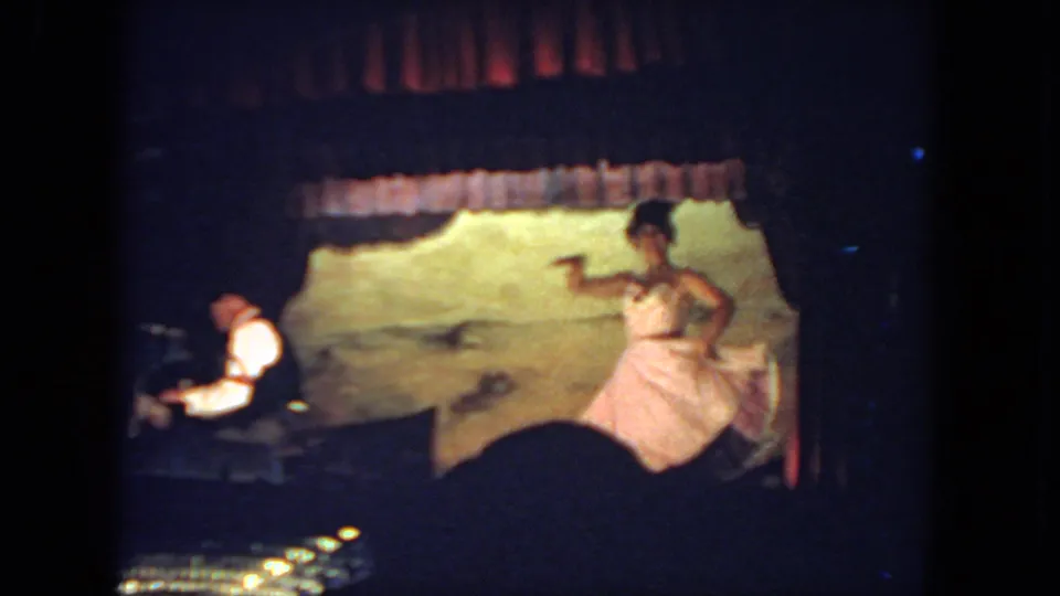 The dancer gestures in a pink ballet-style dress on a small stage, with the pianist visible at left in the 1962 San Diego footage.