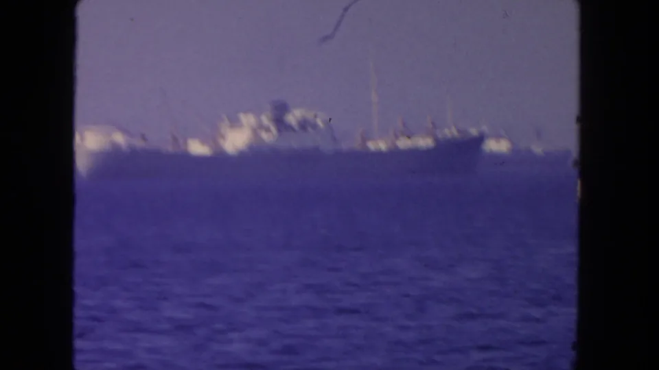 Soft 8mm view of a large ship offshore in San Diego waters, with the sailboat no longer visible in the frame.