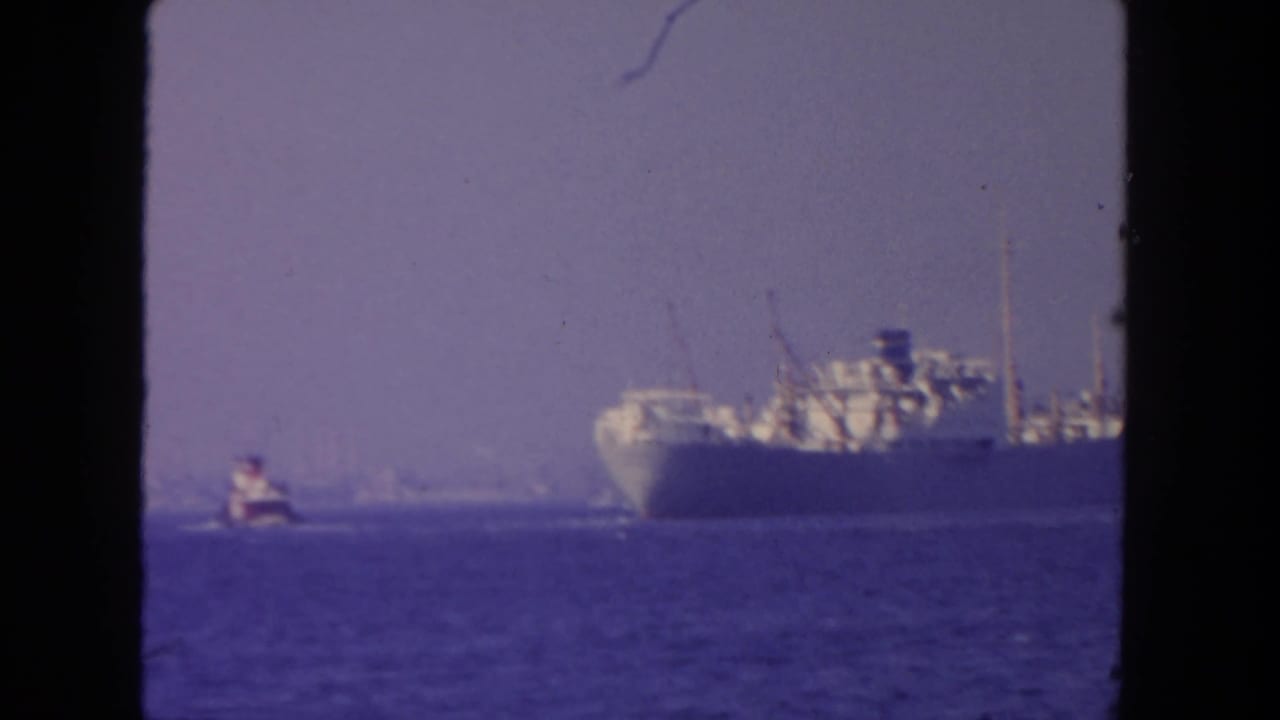 1962 San Diego-area 8mm frame showing a distant steamer on open water with a smaller boat nearby.