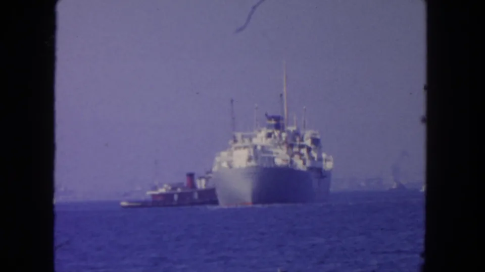 1962 8mm footage, likely San Diego, showing a large passenger ship offshore with a small tugboat nearby in hazy light.