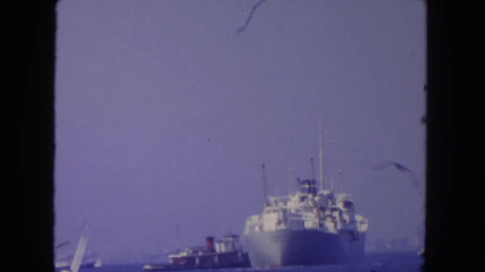 Likely San Diego 1962 harbor footage showing a passenger ship, tugboat, and small sailboat under a hazy sky.