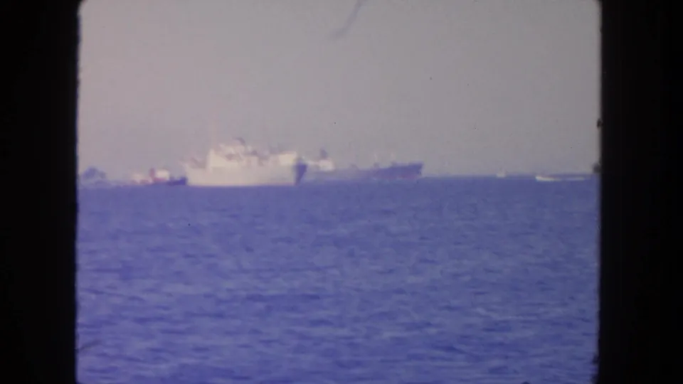 1962 San Diego 8mm frame emphasizing open water and pale ships on a hazy horizon.