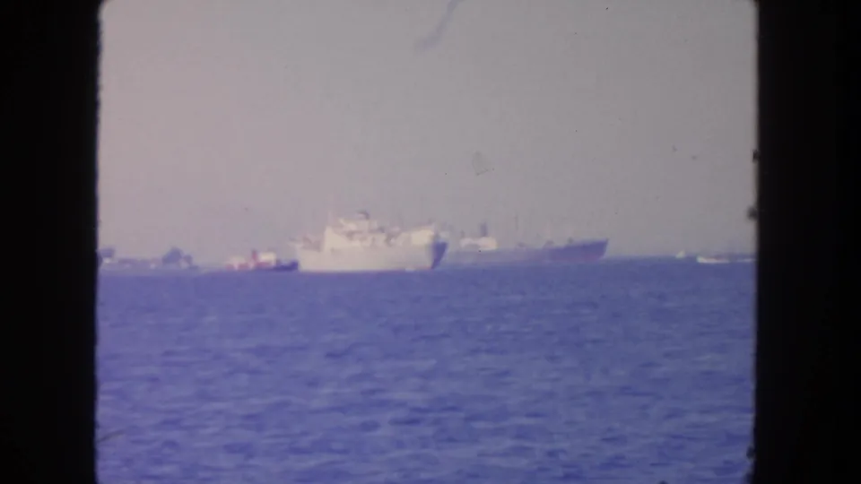 1962 San Diego home-movie frame showing distant white ships across calm ocean water.