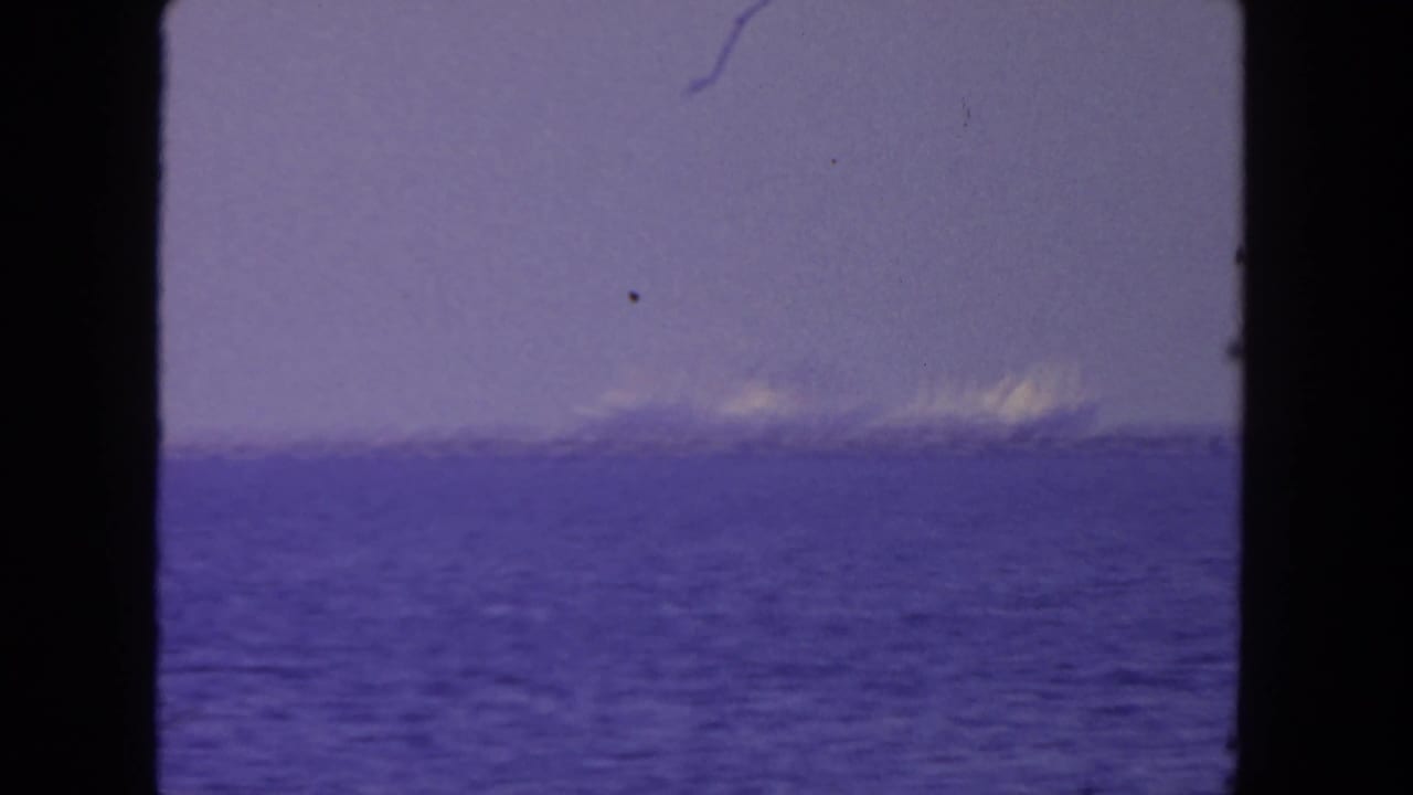 Distant ships on a hazy horizon across blue ocean water.