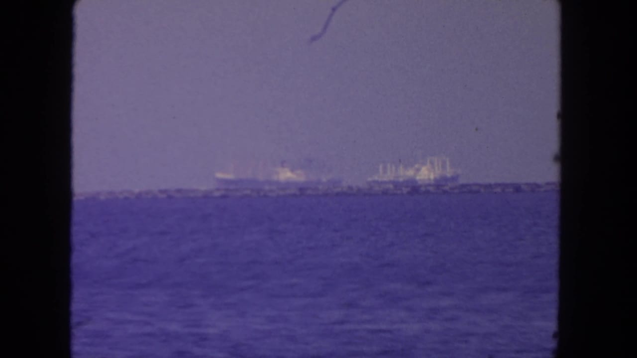 Hazy 8mm view of ships off San Diego, with open water filling the foreground and vessels near the horizon.