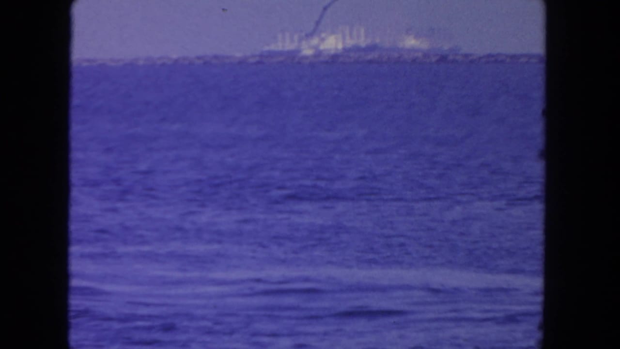 1962 San Diego 8mm frame showing a distant large ship across open water under a hazy sky, with visible film gate borders.