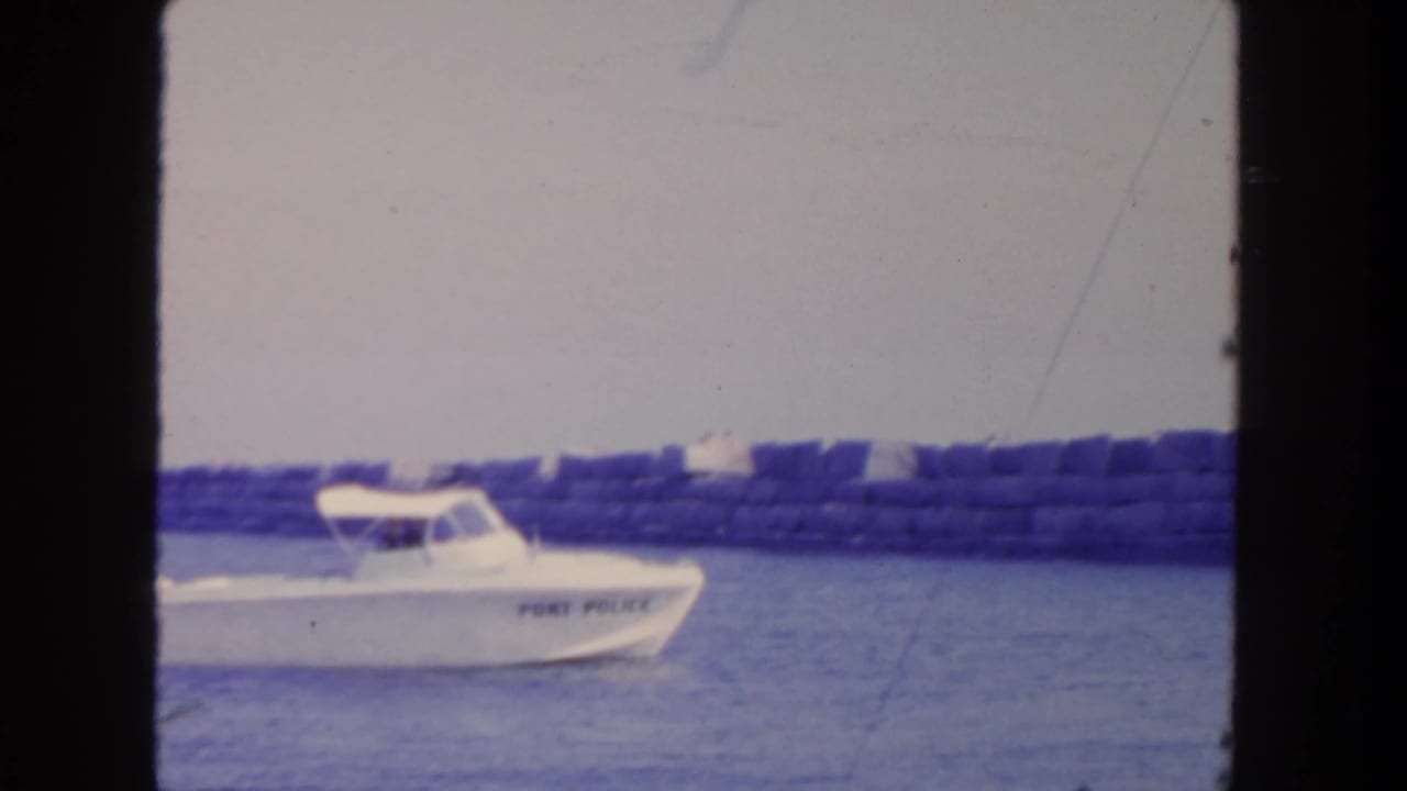 Port Police boat continues along the water with breakwater in the background.