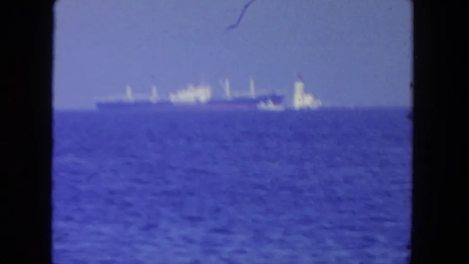 A distant maritime view shows a large ship and a lighthouse-like structure on the horizon across blue water in the San Diego clip.