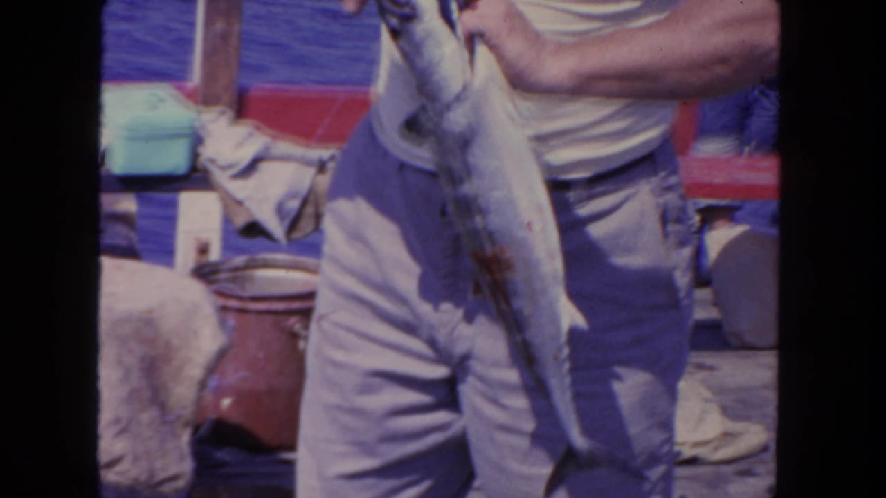 Close view of a man holding a large fish on a boat deck.