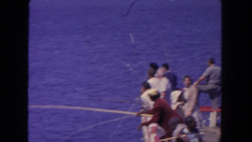 1962 San Diego home-movie frame showing several people with fishing rods along a pier above blue water.