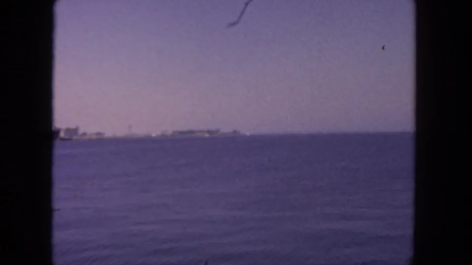 1962 San Diego harbor view across open water with distant vessels under a faded purple sky.