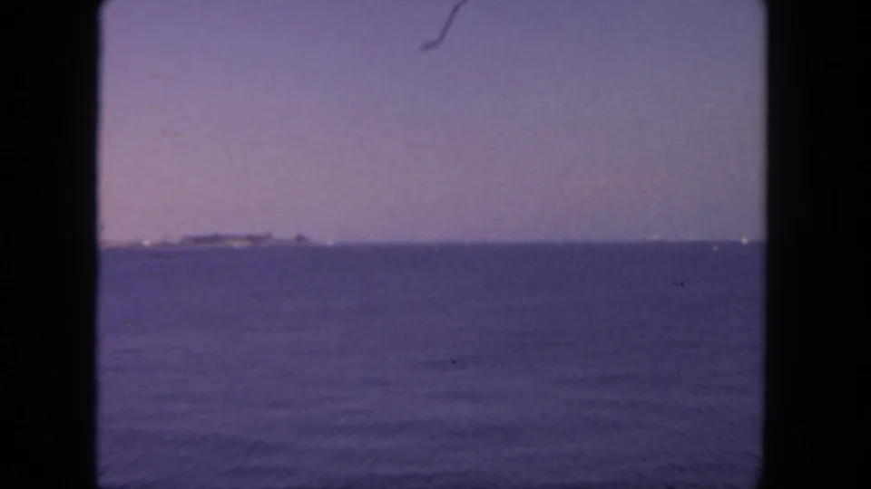 A distant vessel and low shoreline appear across the water in this faded 1962 San Diego harbor frame.