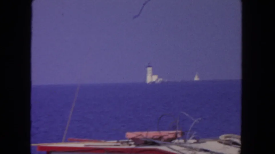 1962 San Diego 8mm frame showing the fishing boat deck and rail area with open blue water and distant coastal markers.