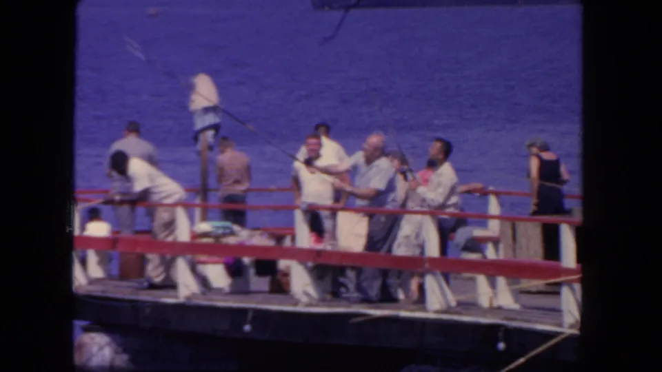 1962 San Diego fishing-boat scene with adult men in light clothing handling rods on deck against the open sea.
