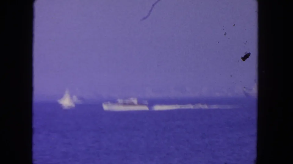 Offshore view in San Diego showing a sailboat and motorboat on hazy blue water in a 1962 home-movie frame.