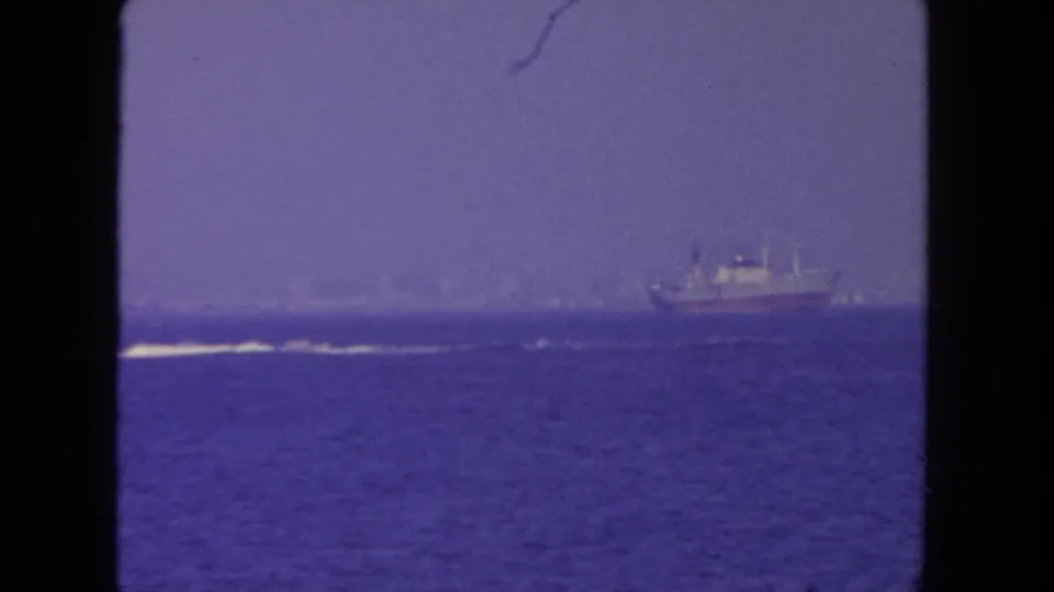 Distant boat on blue water in a soft, grainy 1962 San Diego 8mm coastal view.