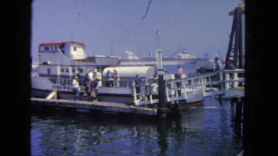 Passengers gather near the gangway of a white-and-red boat at a San Diego harbor dock in 1962 home-movie footage.