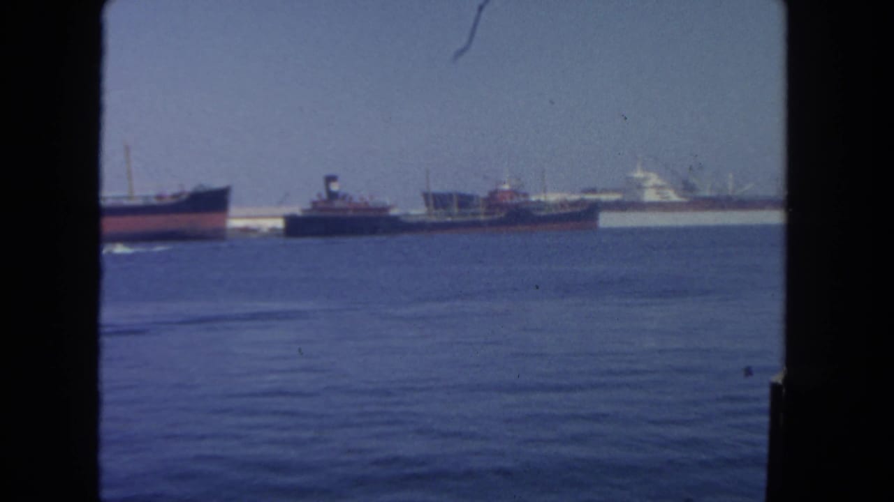 San Diego harbor footage from 1962 showing anchored commercial ships across blue water, seen through dark vertical framing.