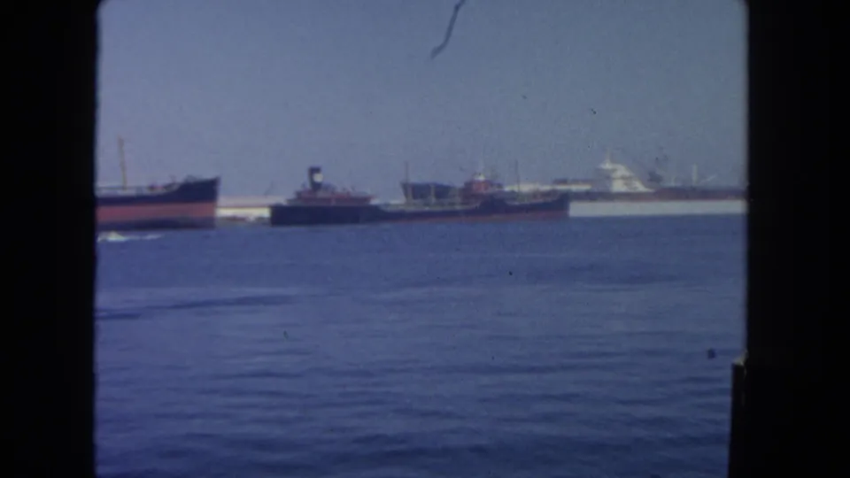 San Diego harbor footage from 1962 showing anchored commercial ships across blue water, seen through dark vertical framing.