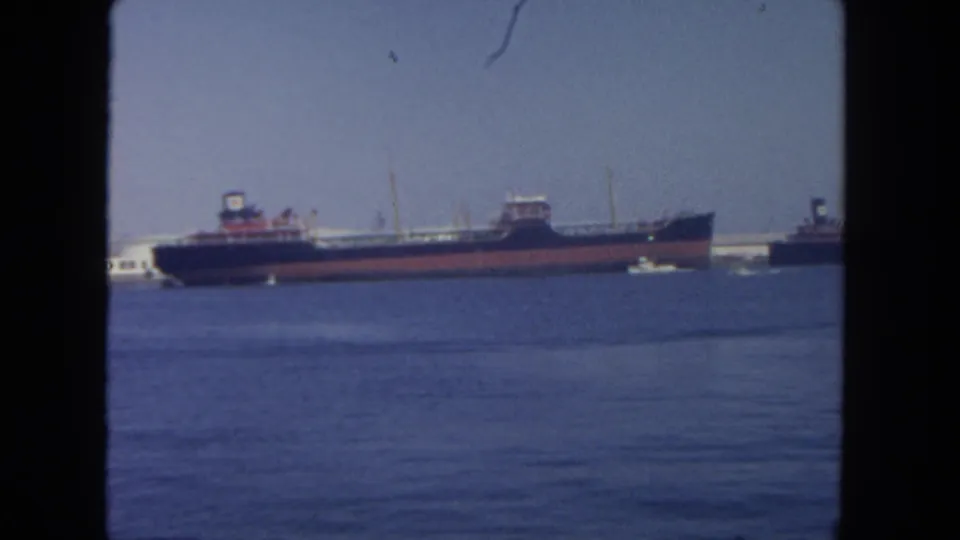 Final 1962 San Diego harbor frame showing the cargo ship, partial Mobil tanker, small white boats, and a second dark vessel at the right edge.