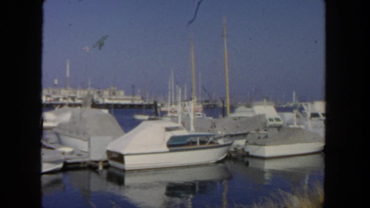 San Diego marina scene from 1962 showing covered small craft, mast lines, docks, and still water reflections.