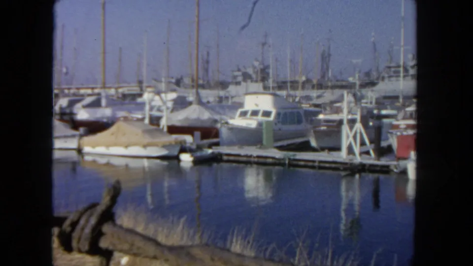 San Diego marina footage from 1962 showing moored small boats, dock posts and reflected masts in blue water.