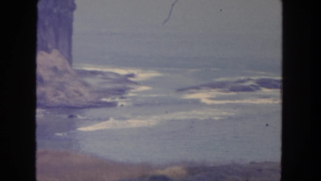 San Diego coastal bluff and ocean surf filmed from a roadside vantage point on muted 8mm color film.