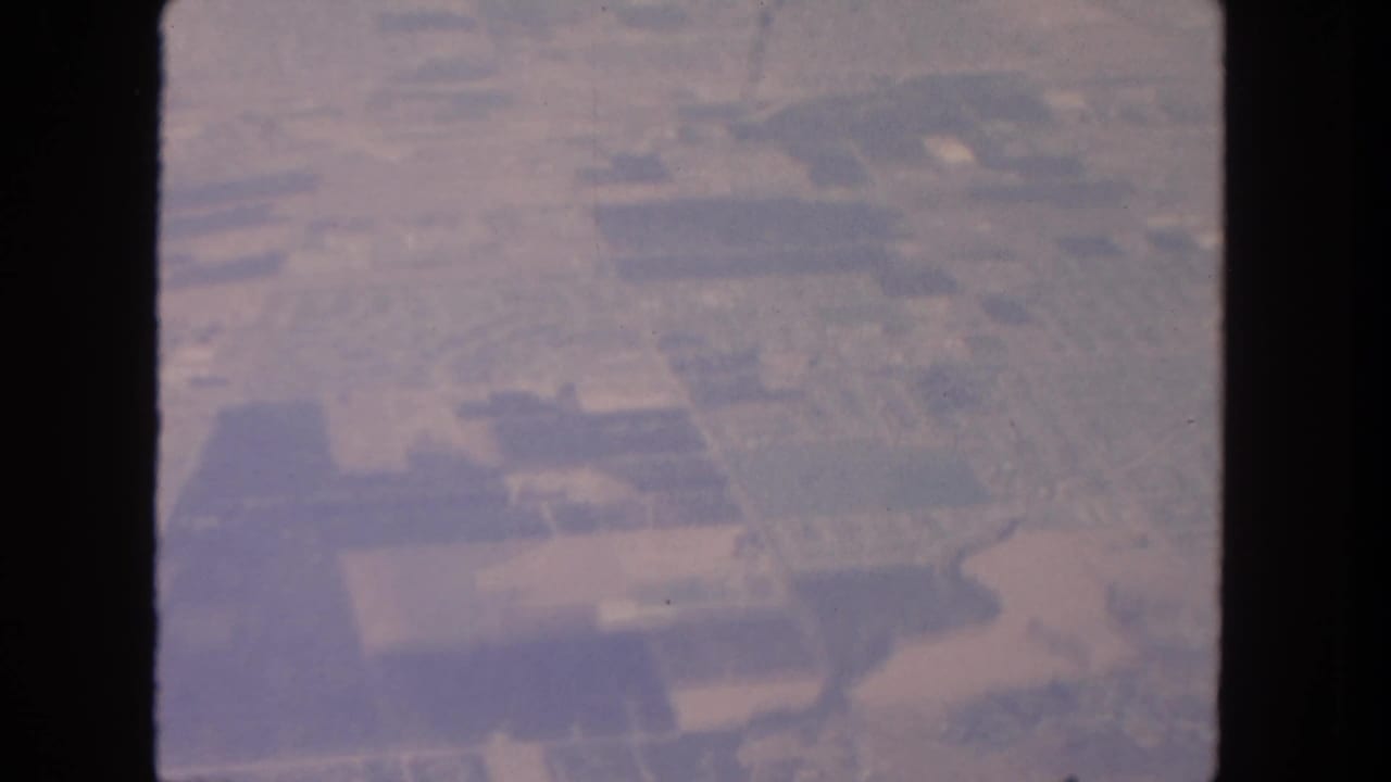Hazy 1962 aerial footage over rural land near San Diego, with fields and roads divided by the contact-sheet frame edge.