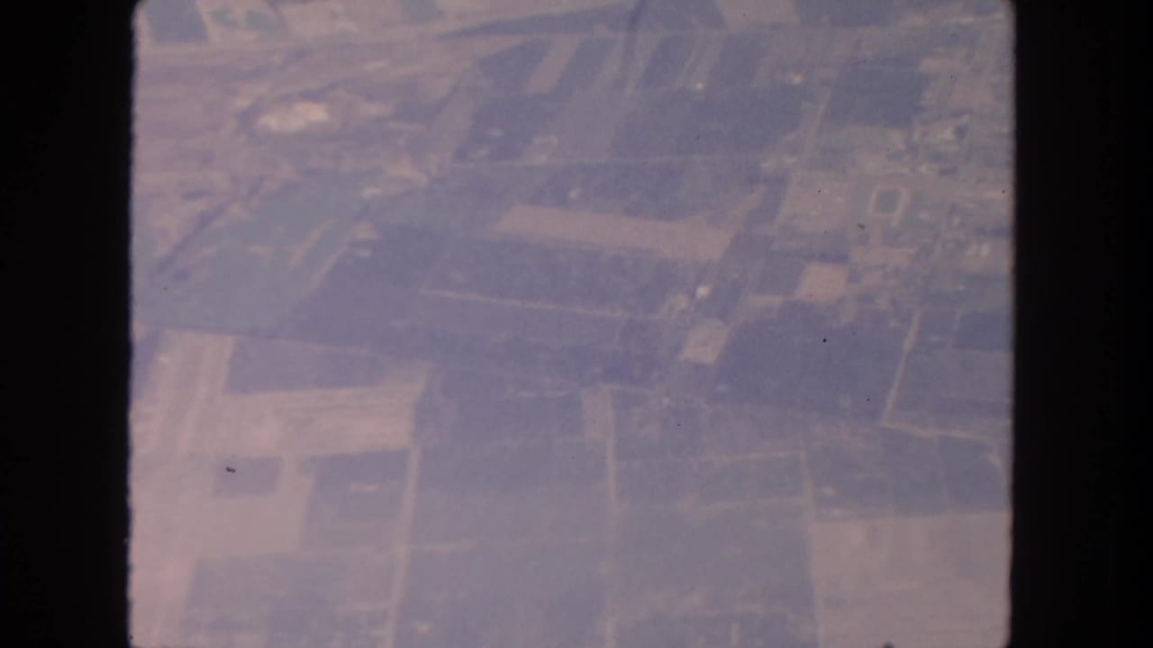 Aerial view of patchwork farmland and dirt roads through dark frame edges.