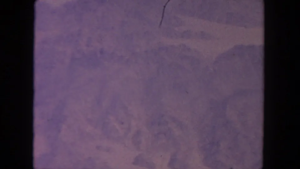 1962 San Diego-associated 8mm frame with soft cloud forms, lavender haze, exposure variation, and aged-film scratches.