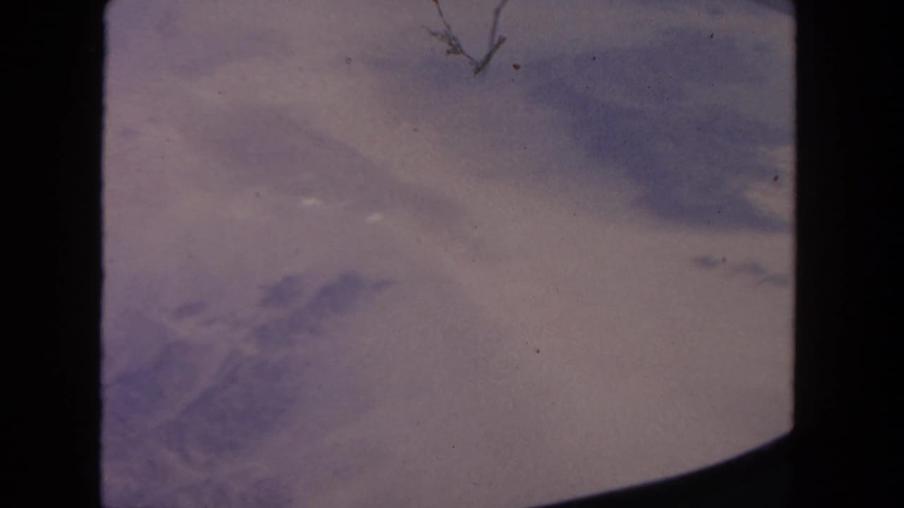 Cloudy sky and distant arid landscape viewed from an airplane window.