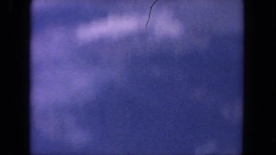 1962 8mm San Diego-area aerial footage with purple-blue sky, diffuse clouds, and heavy dark gate borders.
