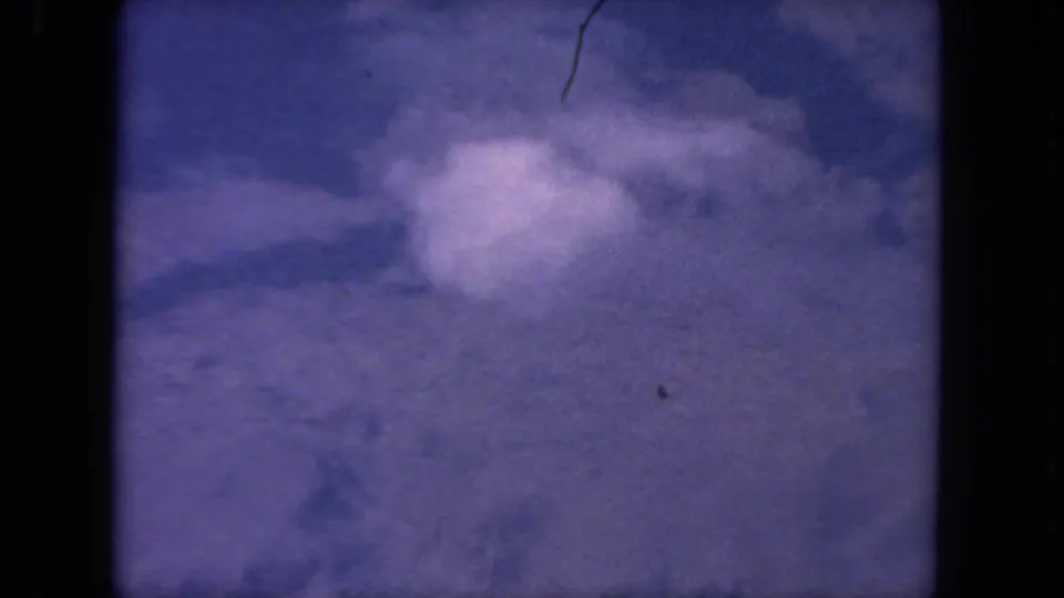 Purple-tinted 8mm aerial view, likely over San Diego-area canyon terrain, with soft clouds and dark frame edges.