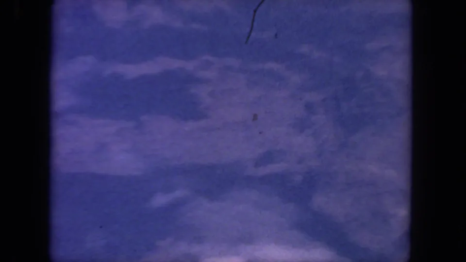 End frame of 1962 8mm aerial footage over a San Diego-area landscape, with purple haze, clouds, and indistinct canyon forms.
