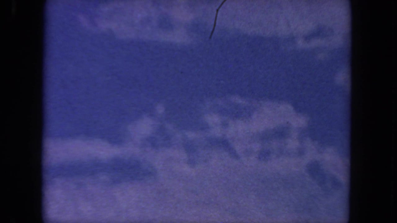 1962 San Diego 8mm frame showing blue sky and diffuse white clouds, with visible gate edges and light film wear.