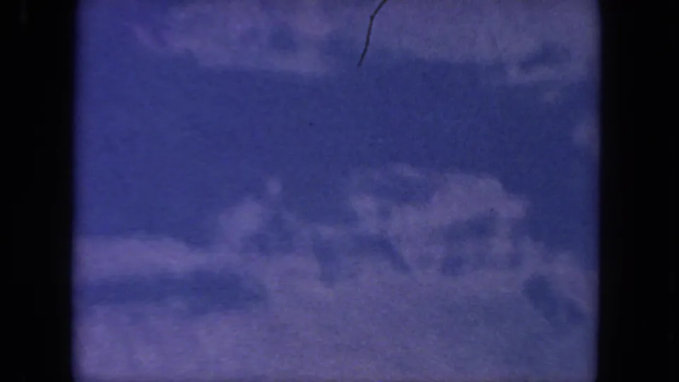 1962 San Diego 8mm frame showing blue sky and diffuse white clouds, with visible gate edges and light film wear.
