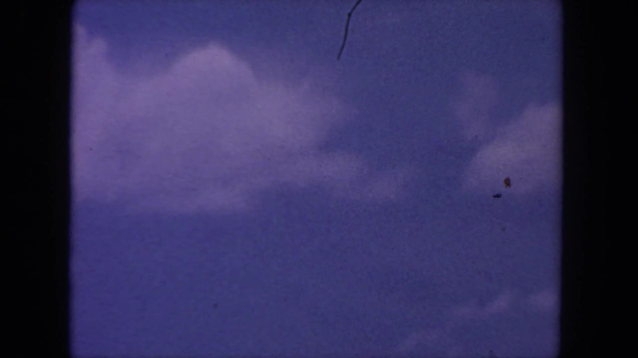 Purple-blue sky with soft clouds, dark film borders, dust, and scratches.